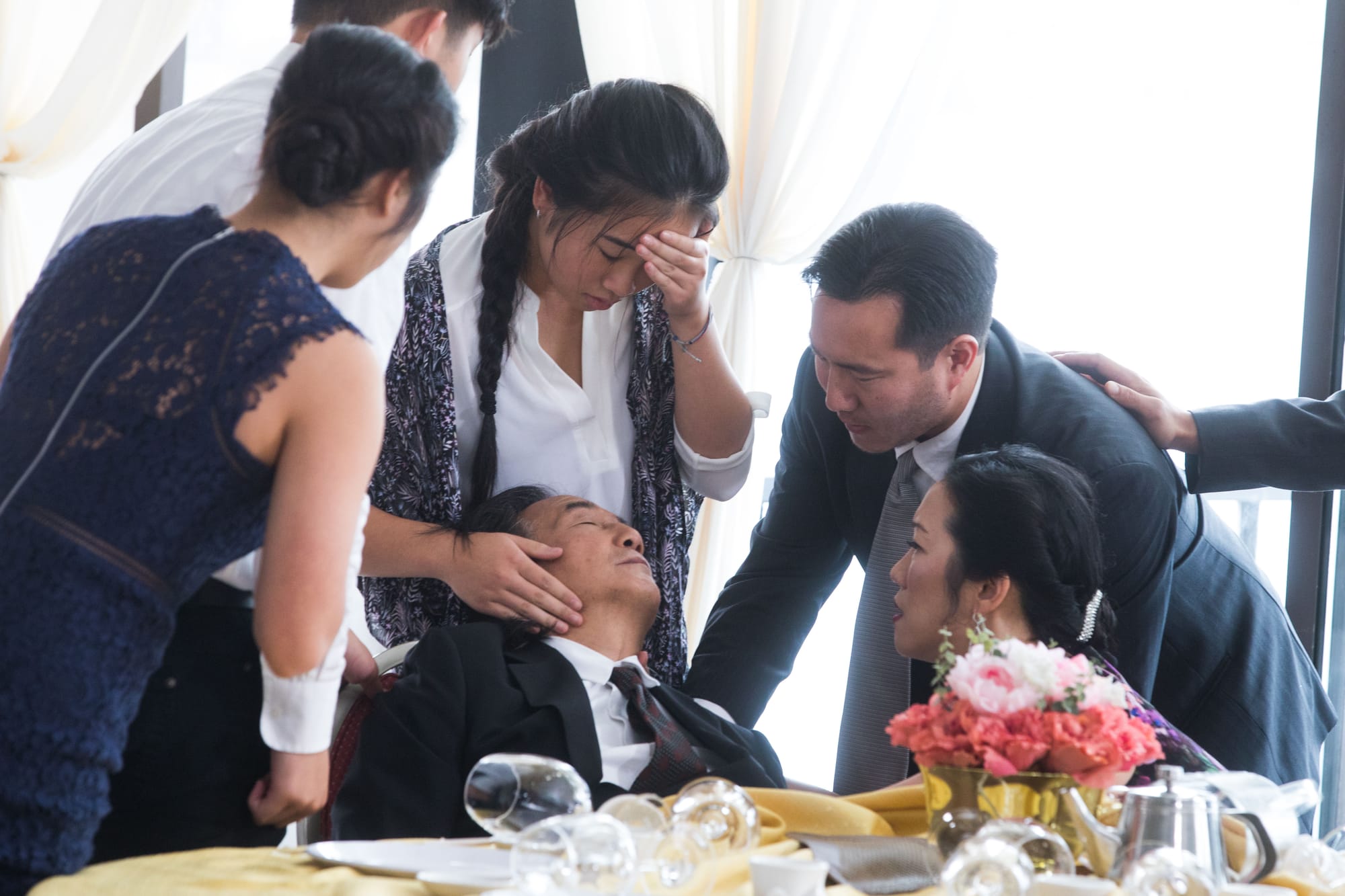 Cast members film a scene around a table