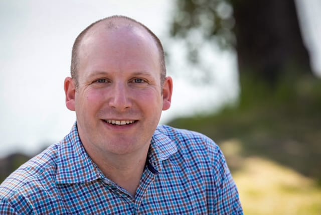 A man in a collared shirt faces the camera
