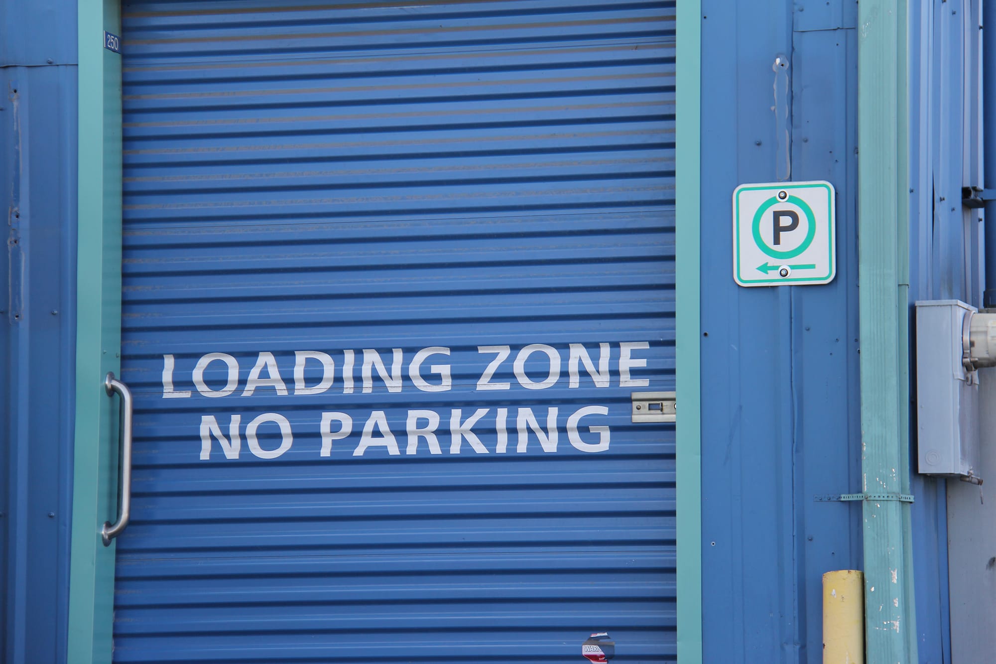 A loading door at a U-Haul store warns motorists not to block access, but a sign posted by the City of Seattle says parking there is OK.