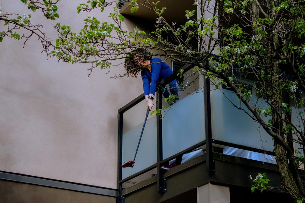 Woman holding phone on selfie stick from balcony