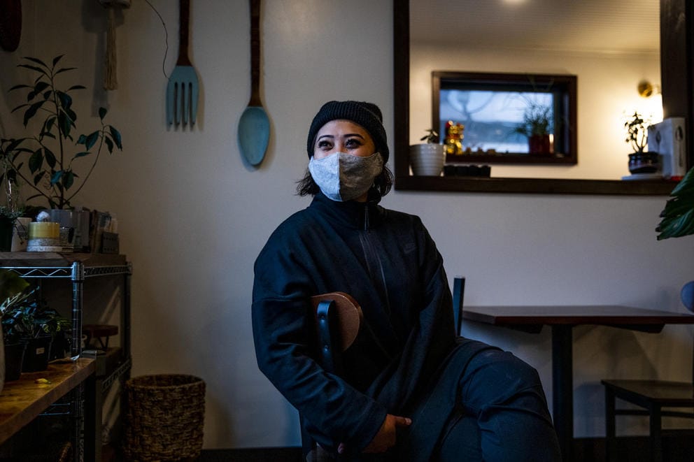 woman with mask sitting on chair, art featuring cutlery on the walls