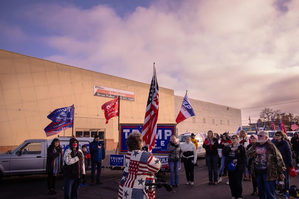 People stand with Trump flags in parking lot
