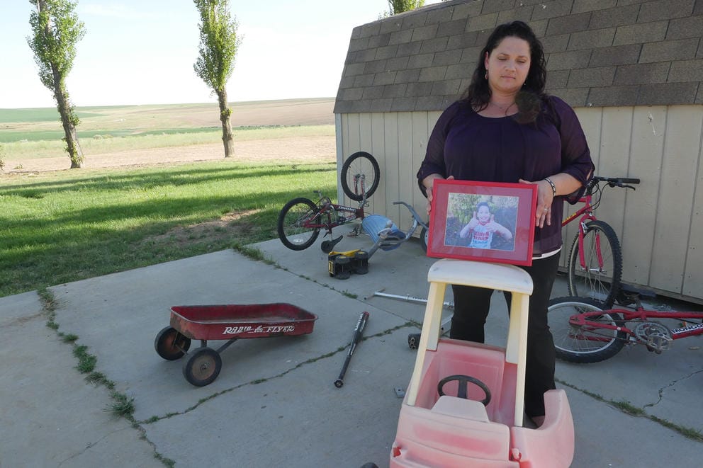 A woman poses with a framed picture of a boy