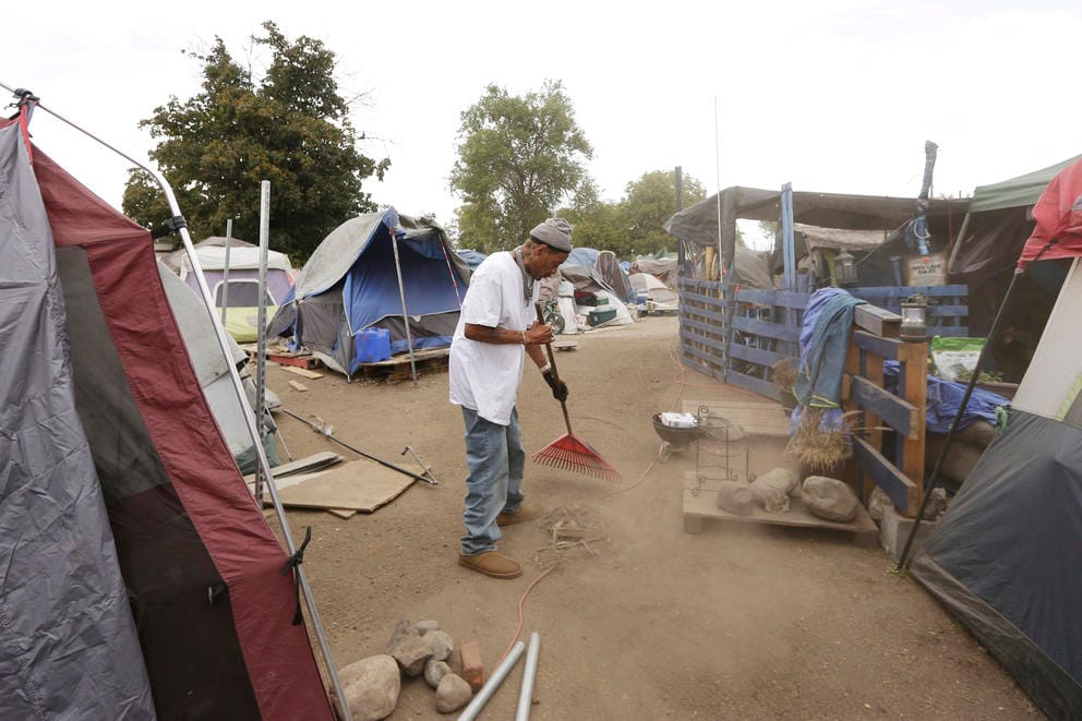 Man cleans a pathway at the Camp Hope encampment