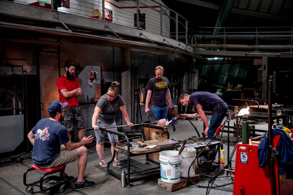 A group of artists work with blown glass