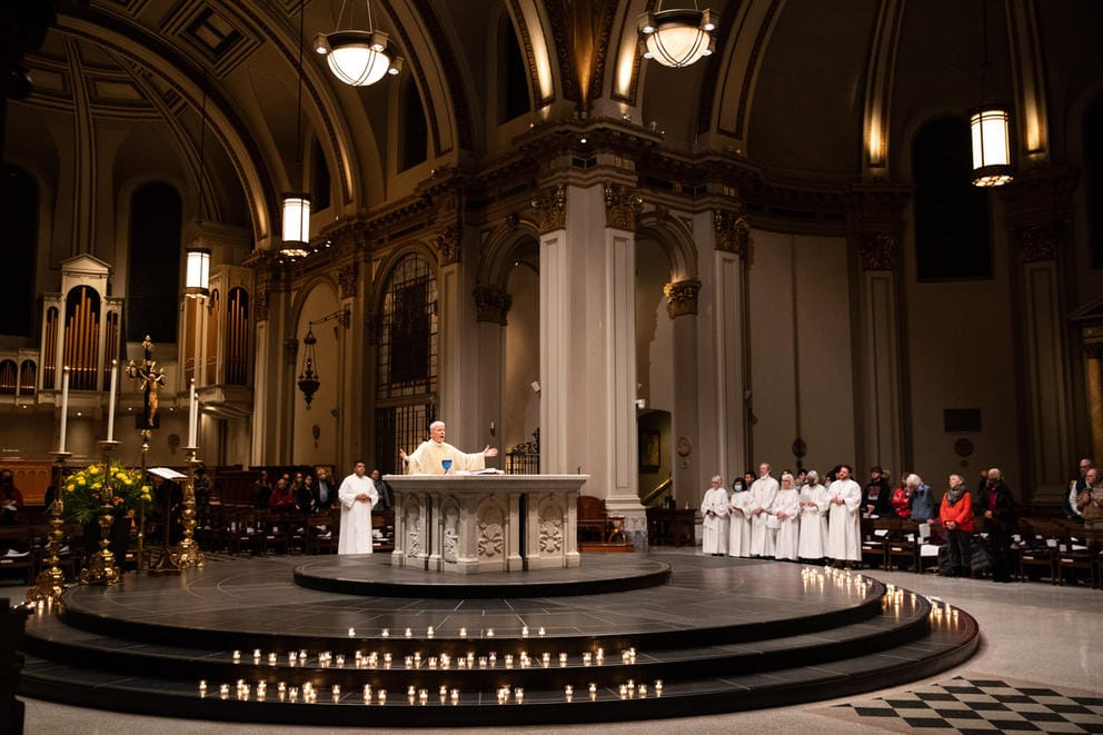 a priest in white robes presides over a mass inside a cathedral in Seattle