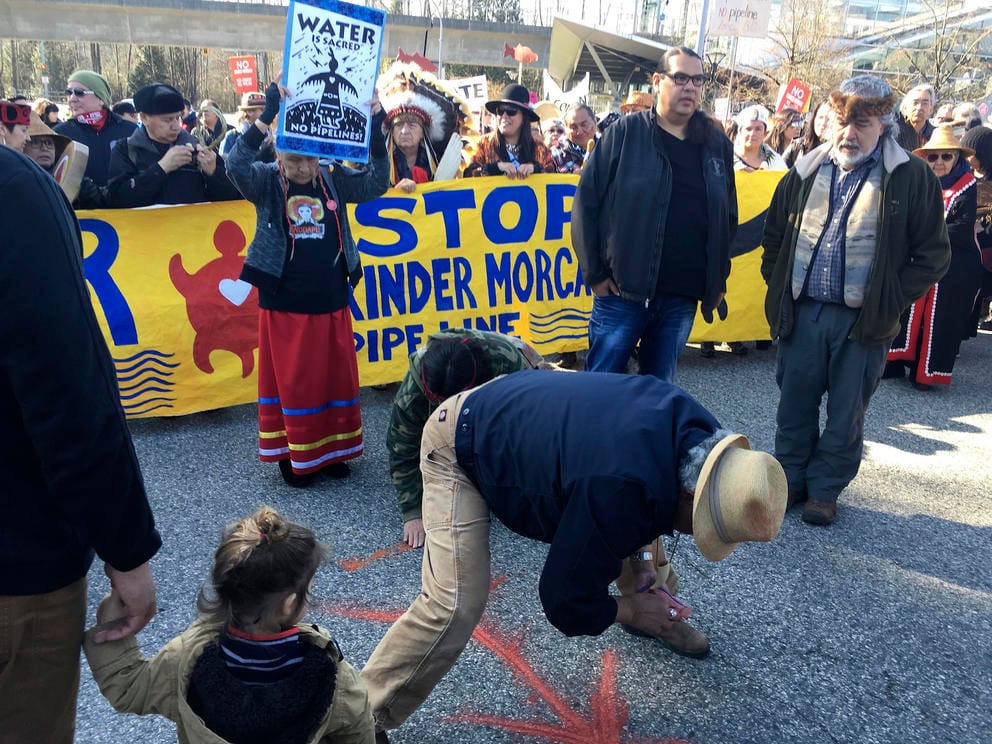 People gather in front of a yellow sign