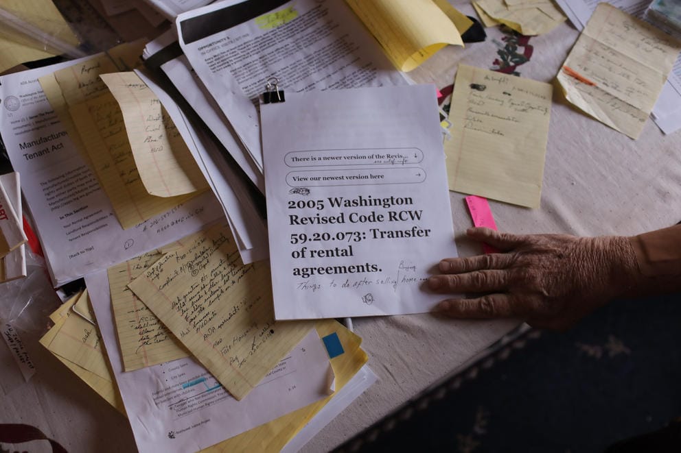 A hand on paperwork on a cluttered desk