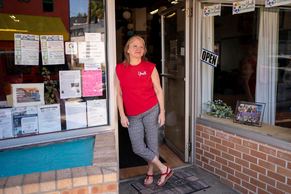 Kirchoff, wearing a red shirt, poses in the storefront doorway of The Youth Connection