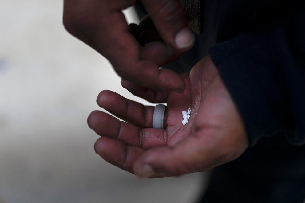 The picture shows a crushed and powdery white substance in the palm of a hand.