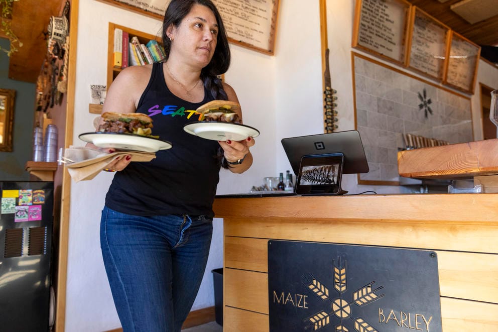 Forteza carries two plates of food out from behind the counter.
