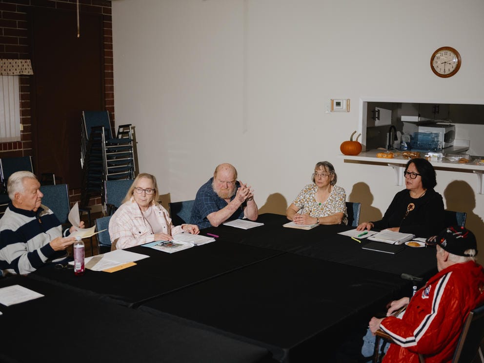 A group of tenants sit around folding table in their community clubhouse