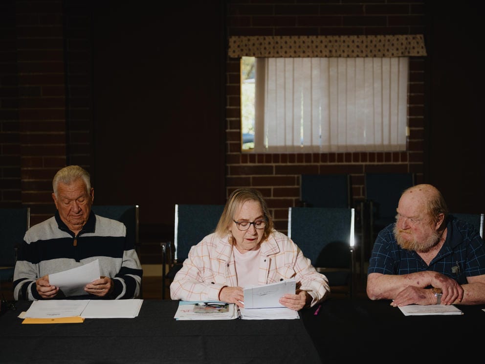 Three tenants sit along one side of a meeting table