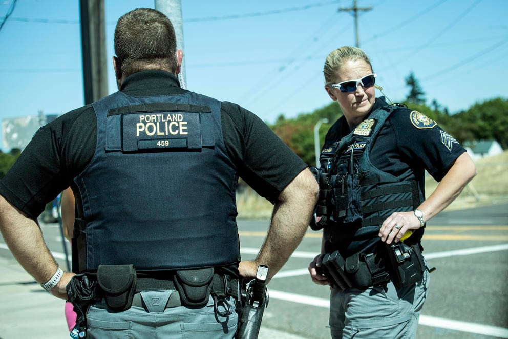 Two police officers face each other as they talk to someone off-camera