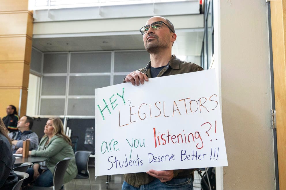 A man stands with a sign that reads