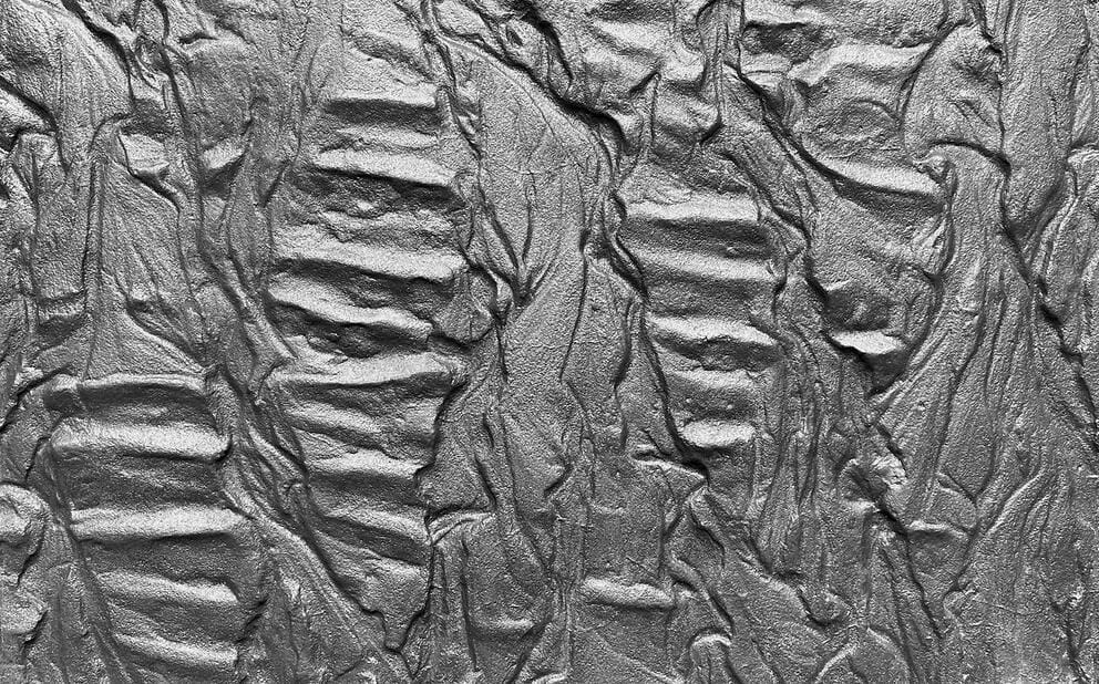 close up on an abstract cement artwork, organic ripples in a graphite sheen