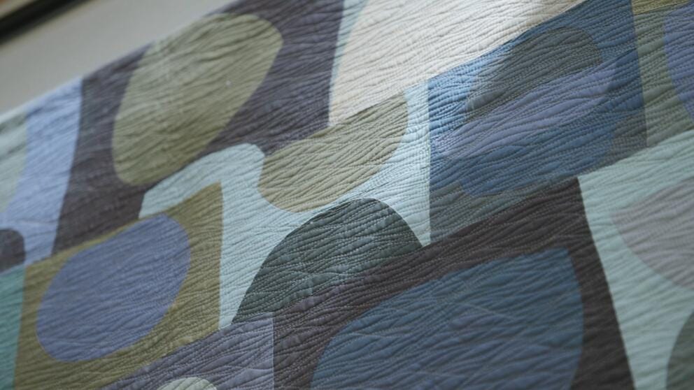 close up on a quilt of gray and green abstract geometry