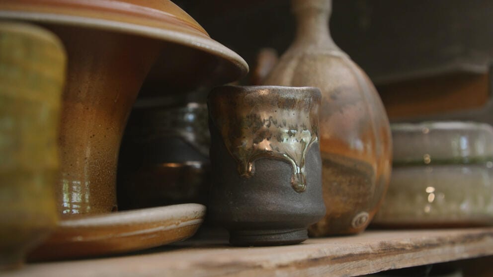 a shelf full of organically hued pottery