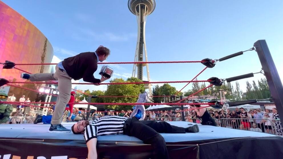 photo of a wresting ring in front of the Space Needle, in which someone dressed as Bill Gates enters the ring