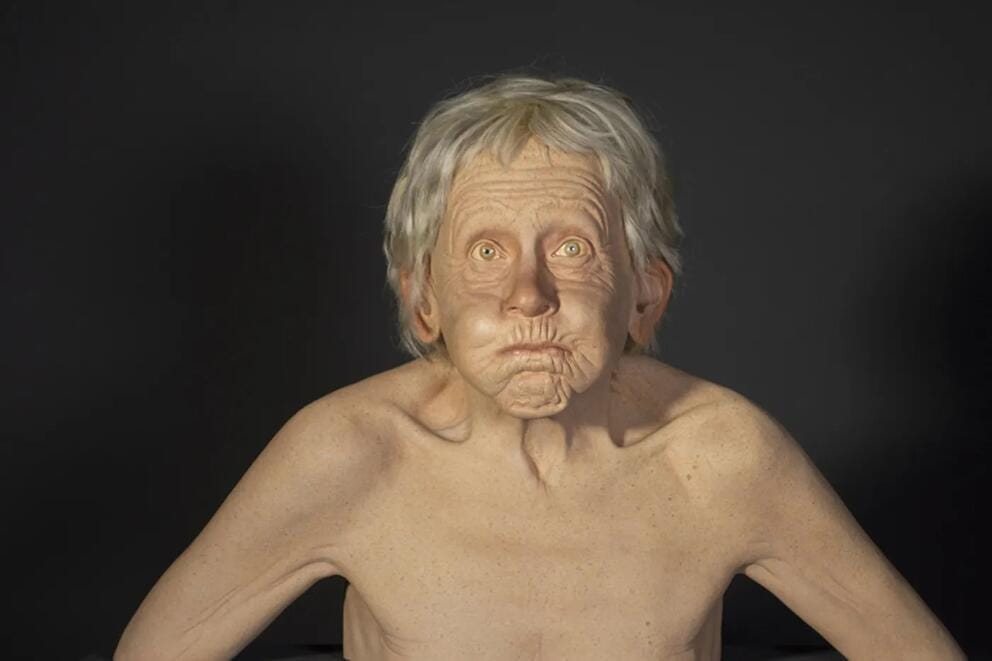 an extremely realistic sculpture of a woman with white hair holding her breath